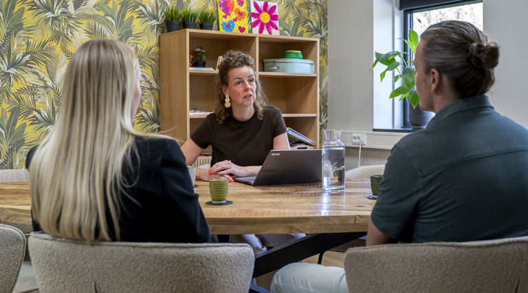 Ouders in gesprek met een behandelaar aan tafel